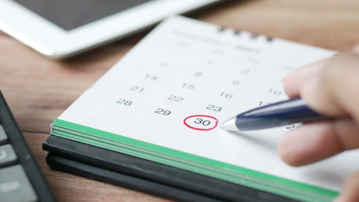 hand circling a date on a desk calendar