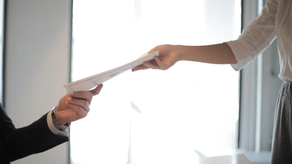 person handing a document to another
