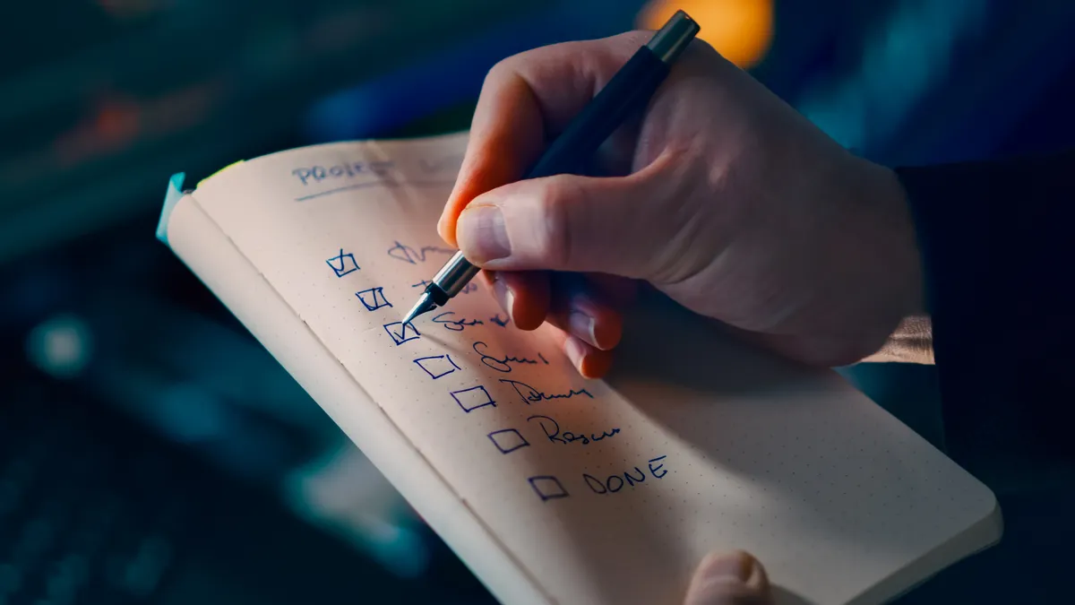 hand ticking items in a notebook checklist