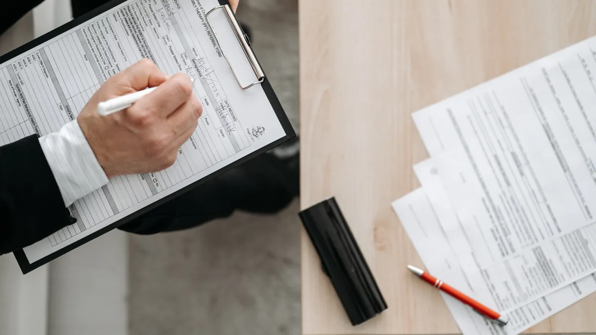 Person filling out forms at a desk