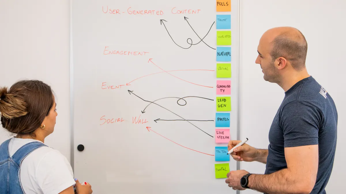 Two people mapping a process on a whiteboard with sticky notes