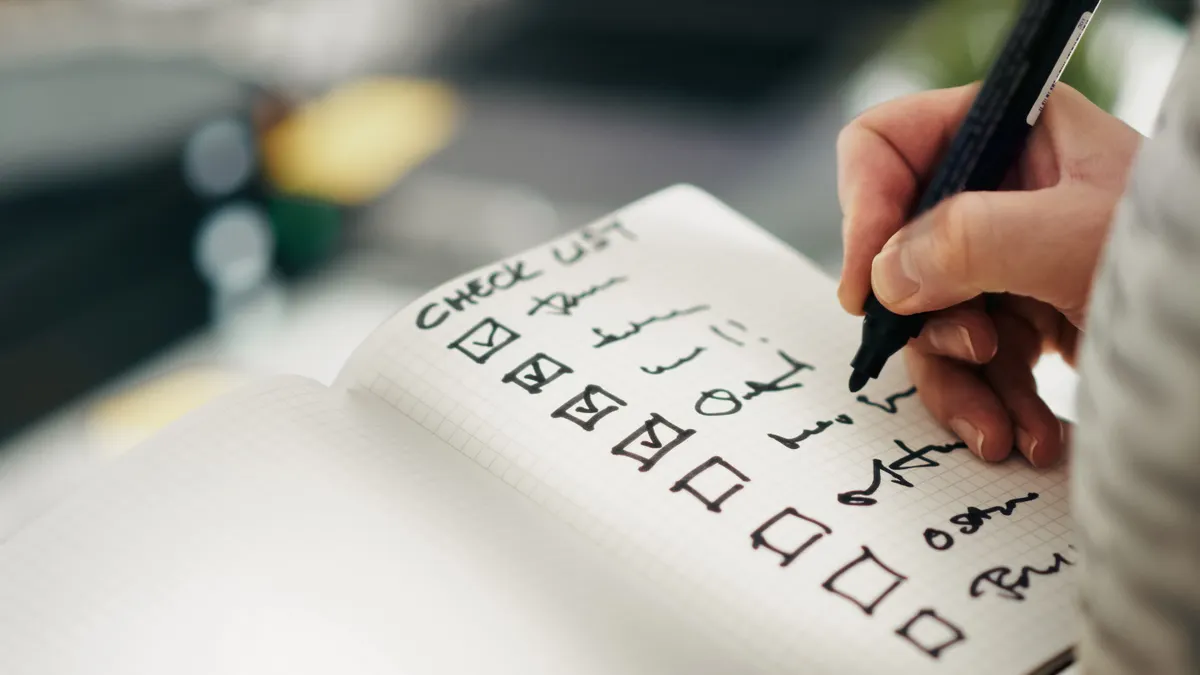 Hand checking boxes in a notebook checklist