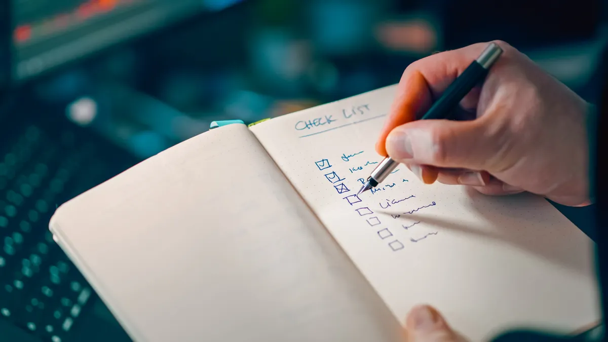 Hand ticking items on a notebook checklist